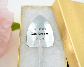 May include: A silver ice cream scoop with a handle shaped like a shovel. The scoop is engraved with the text "Justin's Ice Cream Shovel".