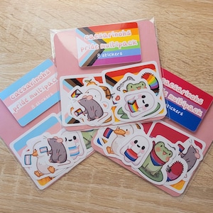 May include: A selection of Pride multipack stickers with animal illustrations. The stickers feature a rat, duck, and frog, each with Pride flags. The packs are labeled with the text "caesarinhs Pride multipack 8 stickers". The stickers are in a pink packet.