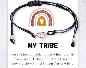 May include: Black friendship bracelet with a silver knot clasp and adjustable cord. The card behind the bracelet has a rainbow graphic and the words "MY TRIBE". The card also includes a quote about friendship.