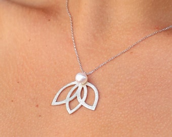 May include: A silver necklace with a delicate chain and a pendant shaped like a lotus flower with a pearl in the center.