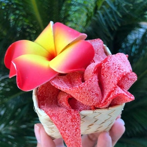 May include: A woven basket filled with red candy, topped with a bright yellow and pink flower.