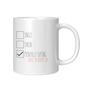 Op de afbeelding: Witte keramische mok met een zwart-witte checklist-ontwerp. De checklist heeft drie opties: single, in een relatie en mentaal met Odell Beckham Jr. samen. De optie mentaal met Odell Beckham Jr. samen is aangevinkt.