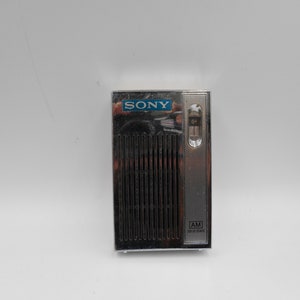 May include: A silver Sony AM transistor radio with a blue logo and a black speaker grille.