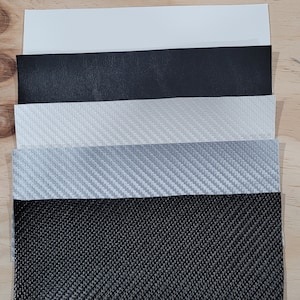 May include: Five different samples of fabric, including black leather, white and gray carbon fiber, and black woven fabric.