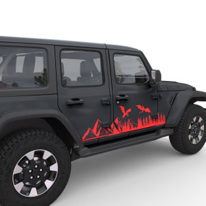 Puede incluir: Jeep Wrangler negro con una calcoman&iacute;a roja de monta&ntilde;a y drag&oacute;n en el lateral. La calcoman&iacute;a presenta una cordillera con dos dragones volando por encima.
