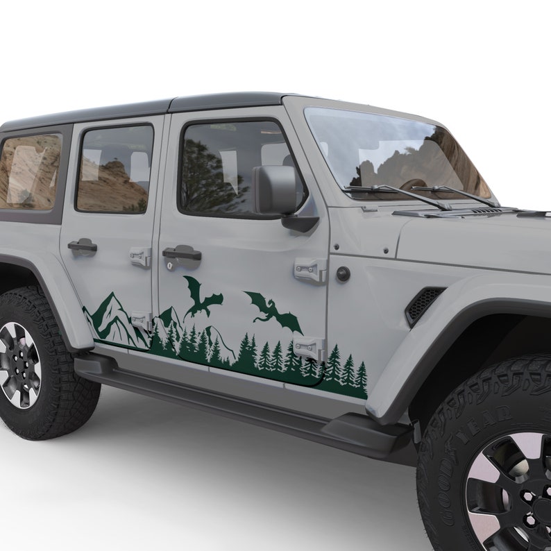 Puede incluir: Un Jeep Wrangler gris con una calcoman&iacute;a de vinilo verde que representa una escena de monta&ntilde;a con dos dragones volando sobre las monta&ntilde;as. La calcoman&iacute;a est&aacute; en el lateral del veh&iacute;culo.