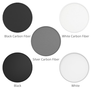 May include: Four round phone grips with different finishes: black carbon fiber, silver carbon fiber, white carbon fiber, and black. The grips are all the same size and shape.