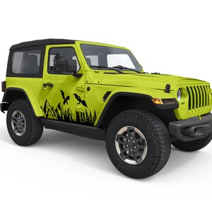 Puede incluir: Un Jeep Wrangler verde lima con detalles negros y una calcoman&iacute;a negra de dos dragones volando sobre una cordillera en el lateral del veh&iacute;culo.