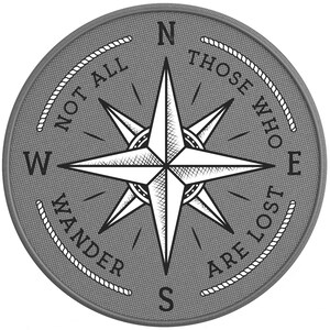 May include: A gray circular compass with a white compass rose and the text "Not all those who wander are lost" around the edge.