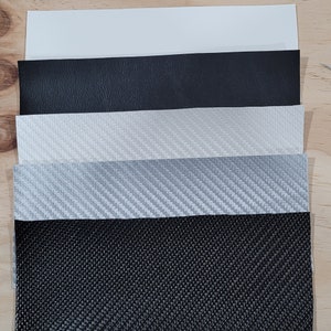 May include: Five different samples of fabric, including black leather, white and gray carbon fiber, and black woven fabric.