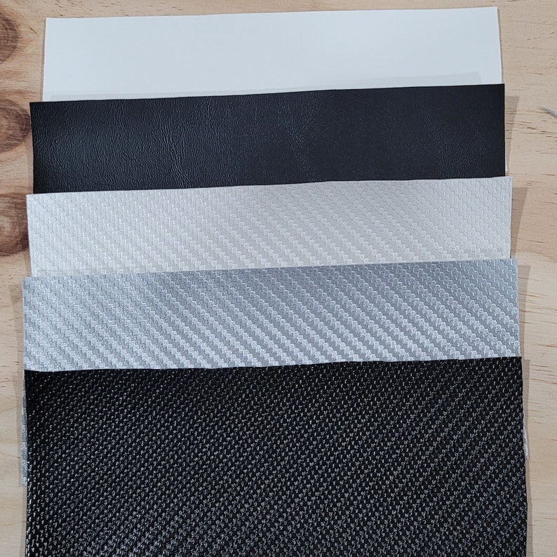 May include: Five different samples of fabric, including black leather, white and gray carbon fiber, and black woven fabric.
