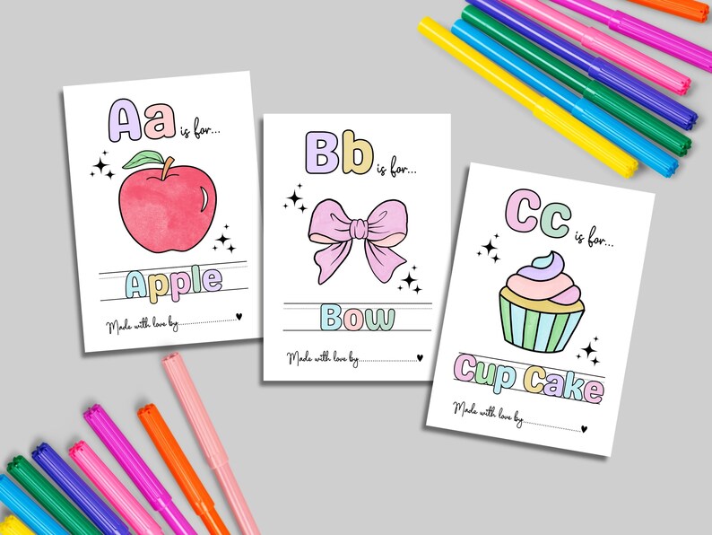Puede incluir: Tres tarjetas ilustradas del alfabeto con las letras A, B y C. La tarjeta A presenta una manzana roja, la tarjeta B un lazo rosa y la tarjeta C una magdalena. Hay rotuladores de colores esparcidos alrededor de las tarjetas.