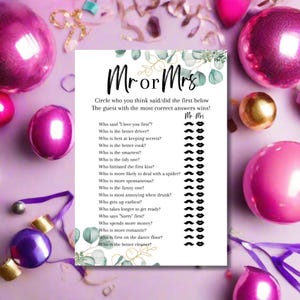 May include: A party game card with the text "Mr or Mrs" and a list of questions to determine who is the best match. The card is decorated with eucalyptus leaves and surrounded by pink and gold party decorations.