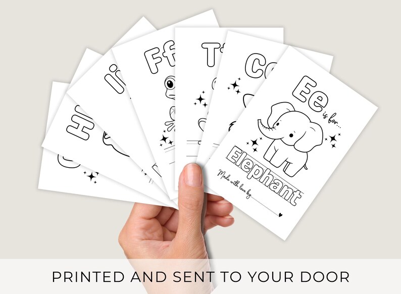 May include: A hand holding a stack of white flashcards with black line drawings and text. Each card features a letter of the alphabet and an associated image, such as an elephant. The text "PRINTED AND SENT TO YOUR DOOR" is at the bottom.