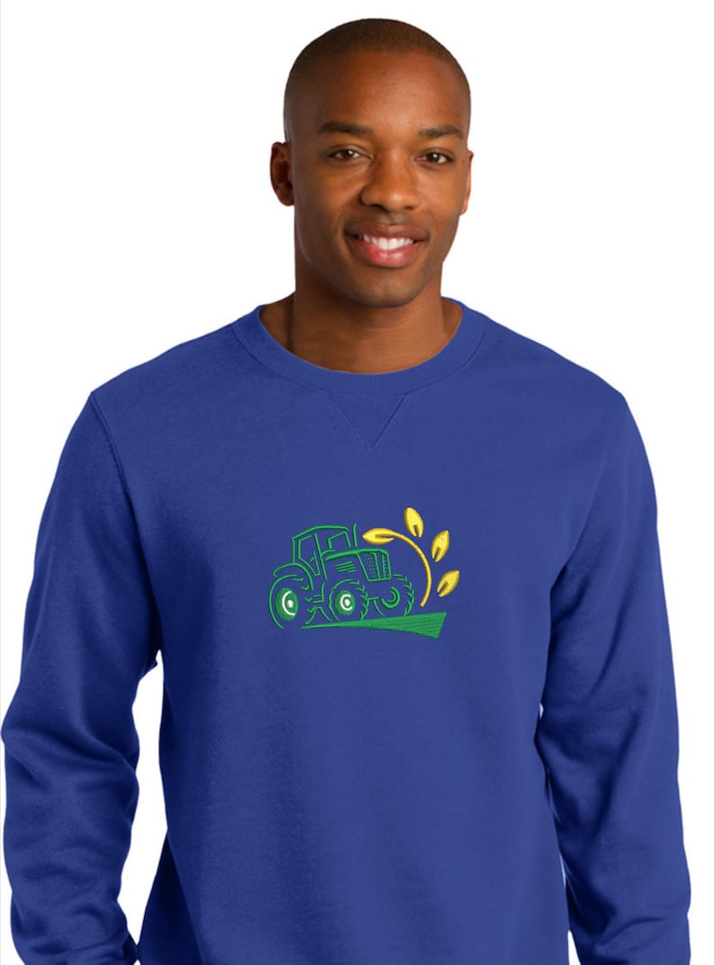 Pode incluir: Uma camisola azul real com um design bordado a verde e amarelo de um trator a puxar um caule de trigo.