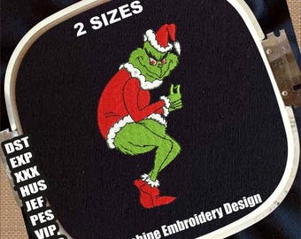 Op de afbeelding: Machine borduurontwerp met een groen personage in een rood kerstmanpak en -muts, met witte rand. Het ontwerp staat op zwarte stof, met de tekst "2 SIZES" en "Machine Embroidery Design".