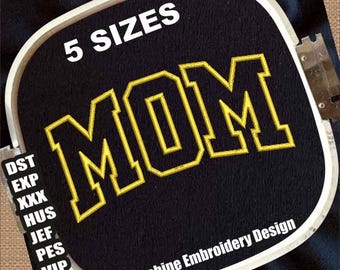 May include: Black fabric with the word "MOM" embroidered in yellow, outlined in white, within a white embroidery hoop. The text "5 SIZES" is above the word "MOM". The words "Machine Embroidery Design" are below the word "MOM".