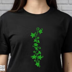 May include: A black t-shirt with a green embroidered design of a vine with leaves. The design is on the left side of the shirt.