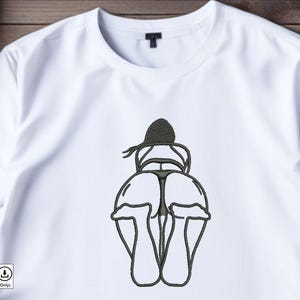 Könnte beinhalten: Ein weißes T-Shirt mit einer schwarzen und weißen Linienzeichnung einer Person, die einen Hut und einen Badeanzug trägt. Die Zeichnung ist auf das Shirt gestickt.