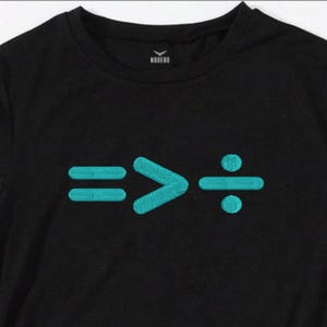 Könnte beinhalten: Schwarzes T-Shirt mit türkisfarbener Stickerei von mathematischen Symbolen: gleich, größer als und Division. Das Oberteil hat einen Rundhalsausschnitt und kurze Ärmel. Der Markenname ist auf dem Nacken gestickt.