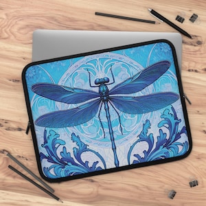 May include: A blue dragonfly with intricate wings is featured on a laptop sleeve. The dragonfly is surrounded by a blue and white floral pattern. The sleeve is made of a soft, durable material and is designed to protect your laptop from scratches and bumps.