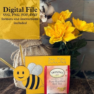 May include: A yellow card with the text "Bee Mine Swee-tea" and a bee illustration. A tea bag with the text "TWININGS HERBAL TEA Pure Rooibos Red Tea" is next to the card.