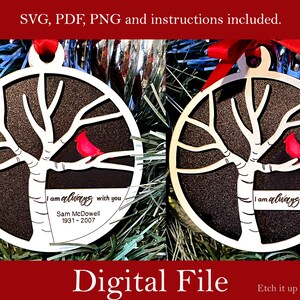 May include: A white wooden ornament shaped like a tree with a red cardinal perched on a branch. The ornament has the text "I am always with you" and "Sam McDowell 1931-2007" on it.