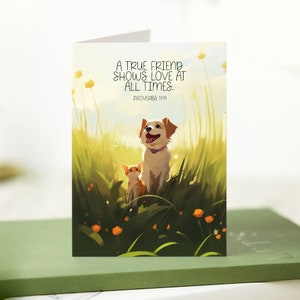 May include: Greeting card featuring an illustration of a dog and a cat in a field of tall grass and orange flowers. The card has the text "A TRUE FRIEND SHOWS LOVE AT ALL TIMES... PROVERBS 17:17". The background is a soft, sunny landscape.