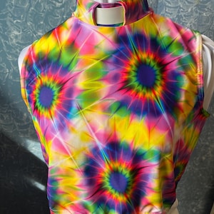 May include: A sleeveless crop top with a high neckline and a vibrant tie-dye pattern. The design features concentric circles in shades of yellow, pink, purple, and green. The top has a keyhole detail at the back of the neck and a fitted elastic hem.