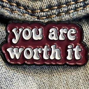 以下が含まれることがあります： 「you are worth it」と白文字で書かれた、えんじ色のエナメルピンです。