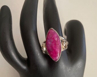 May include: A silver ring with a pink and white marbled gemstone. The ring has a unique, twisted design.