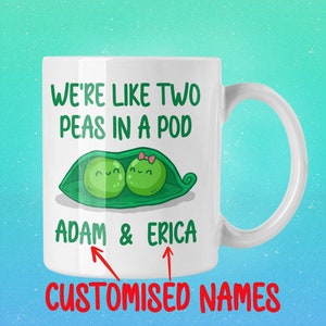 May include: White ceramic mug with a green pea pod design and the text "We're like two peas in a pod". The mug has two smiling peas inside the pod with the names "Adam & Erica" written below. The text "CUSTOMISED NAMES" is written in red at the bottom of the mug.