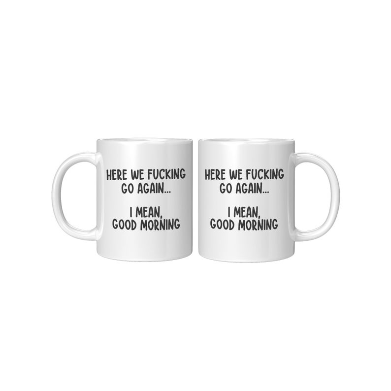 May include: Two white ceramic mugs with black text that reads "HERE WE FUCKING GO AGAIN... I MEAN, GOOD MORNING". Each mug has a white handle and a white interior.