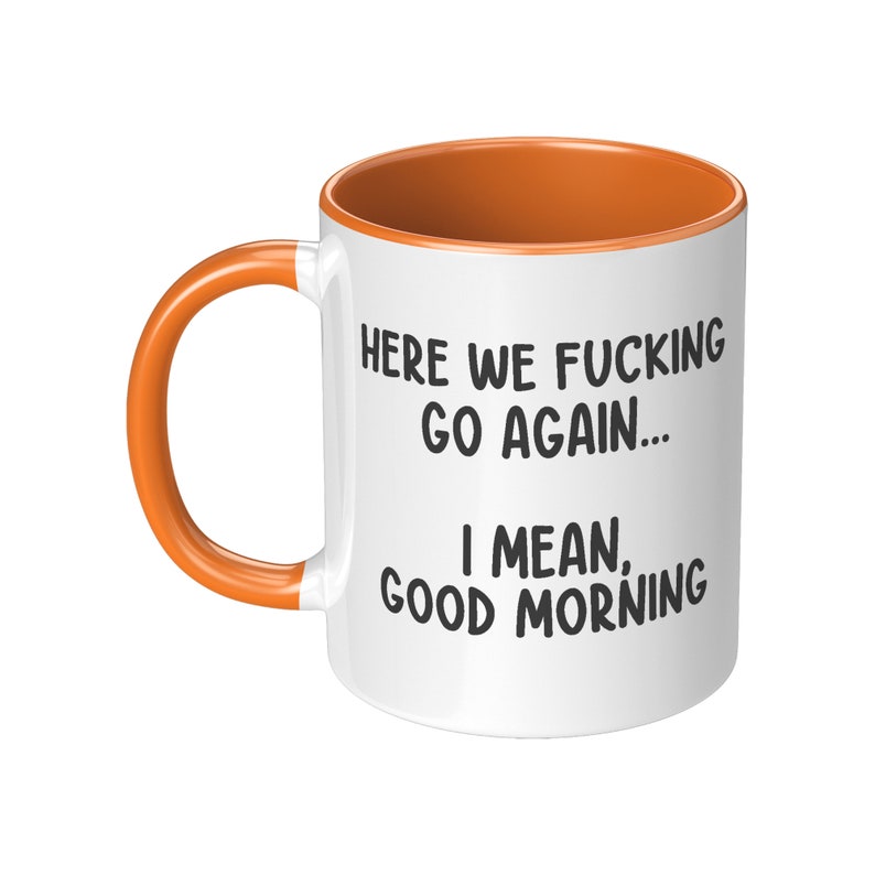 May include: White ceramic mug with an orange interior and handle. The mug features the text "HERE WE FUCKING GO AGAIN... I MEAN, GOOD MORNING" in black, making it a humorous gift.