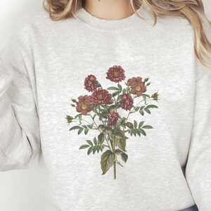 May include: A gray sweatshirt with a floral print of pink and red flowers on the front.