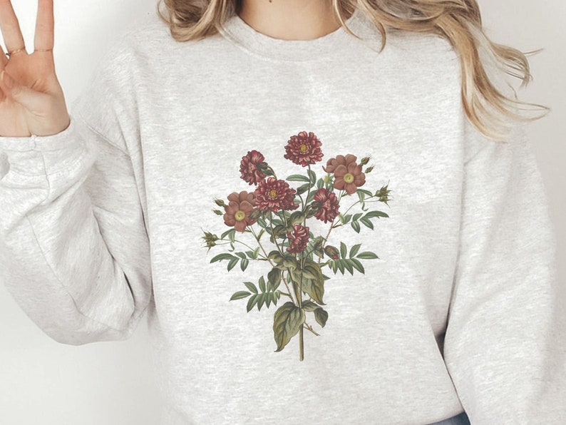 May include: A gray sweatshirt with a floral print of pink and red flowers on the front.