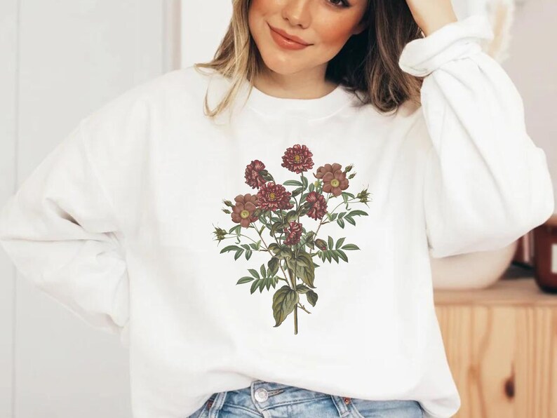 May include: White sweatshirt with a floral print of pink and red flowers on a white background.
