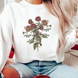 May include: White sweatshirt with a floral print of burgundy roses and leaves.
