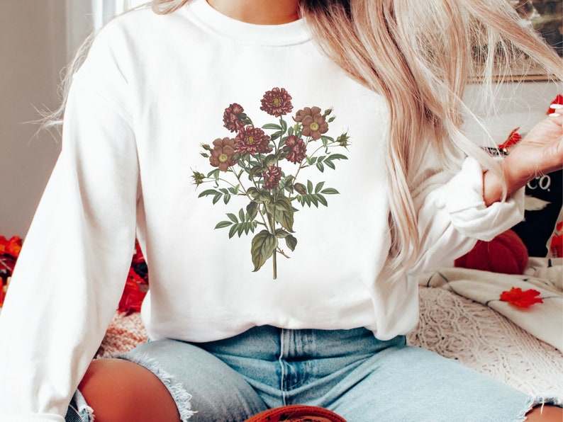 May include: White sweatshirt with a floral print of burgundy roses and leaves.