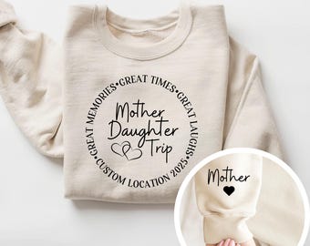 Puede incluir: Sudadera beige con el texto "Mother Daughter Trip" en un diseño circular. El diseño incluye corazones y las palabras "Great Memories, Great Times, Great Laughs, Custom Location 2025." La manga tiene la palabra "Mother" y un corazón.