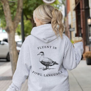 May include: A gray hooded sweatshirt with the text "Fluent in Fowl Language" and a black and white illustration of a duck on the back.