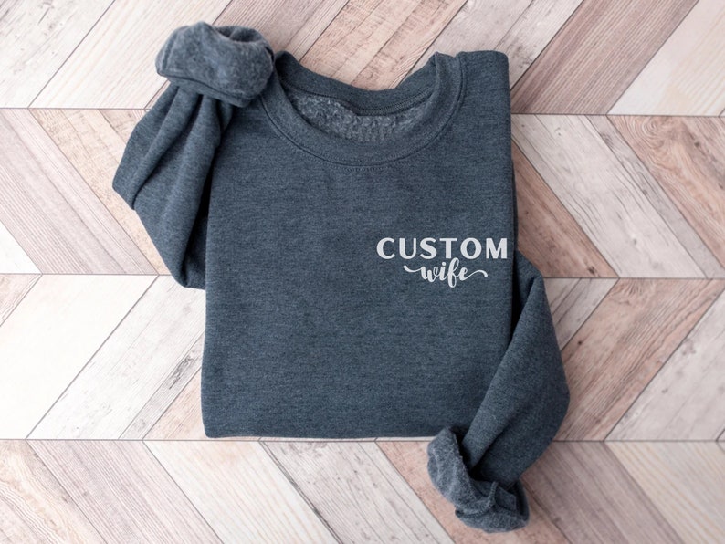 May include: A dark gray sweatshirt with the text "CUSTOM wife" in white lettering.
