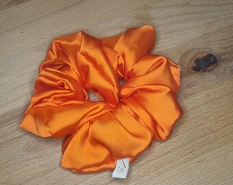 May include: Orange satin scrunchie with a small white tag.
