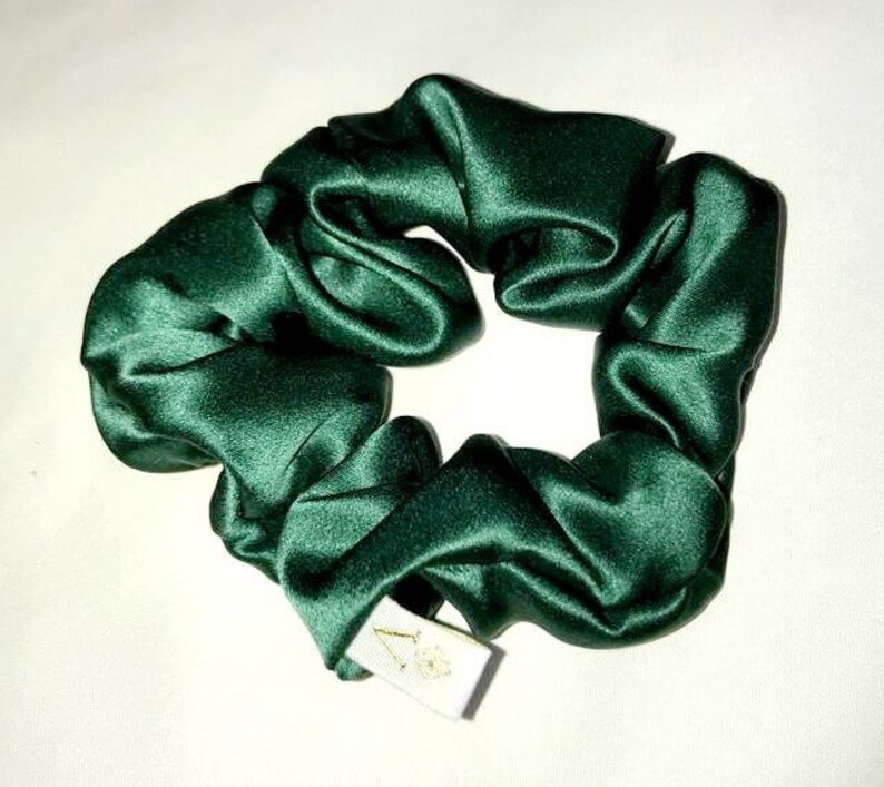 May include: A dark green satin scrunchie with a white tag.