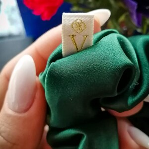 May include: A green satin scrunchie with a white tag that says "V" in gold glitter.