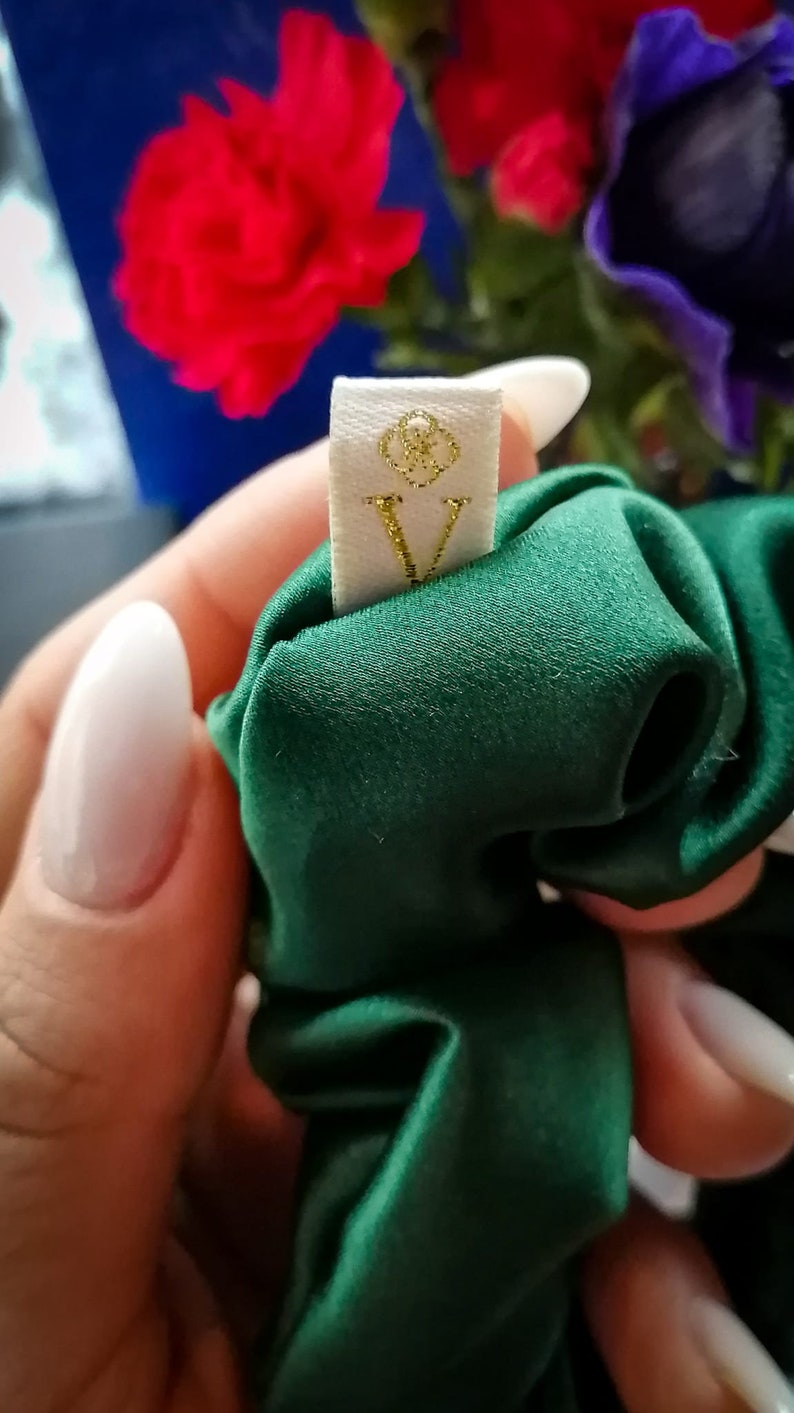 May include: A green satin scrunchie with a white tag that says "V" in gold glitter.