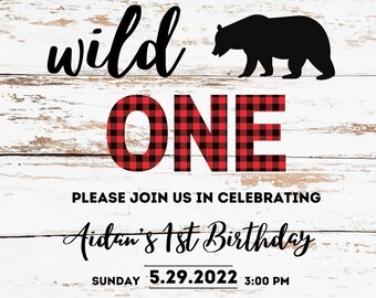 May include: A white wood background with a red and black plaid "ONE" and a black silhouette of a bear. The text "OUR LITTLE BEAR IS A WILD" is above the plaid "ONE". The text "PLEASE JOIN US IN CELEBRATING Aidan's 1st Birthday" is below the plaid "ONE". The text "SUNDAY 5.29.2022 3:00 PM OUR HOUSE 123 MAIN ST. CITY, STATE RSVP: ASHLEY 123-456-7890" is below the text "Aidan's 1st Birthday". The bottom of the image has a row of green pine trees.