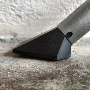 May include: A black plastic vacuum cleaner attachment with a triangular nozzle. The nozzle is designed to clean tight spaces and corners.