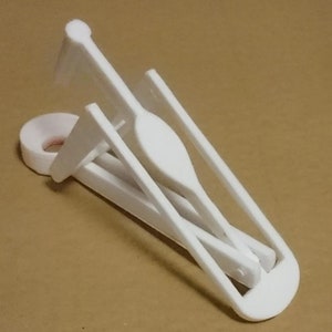 以下が含まれることがあります： 丸い開口部とヒンジ付きの腕を持つ白いプラスチッククリップ。クリップは、紙、写真、布など、さまざまなアイテムを保持するように設計されています。