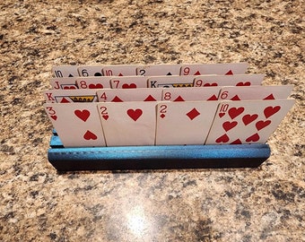 May include: A blue wooden card holder with a stack of playing cards. The cards are arranged in a fan shape and show the numbers 10, 6, 10, 10, 2, 19, 9, 8, 6, 10, 3, 2, 2, 8, 2, 10. The cards are all hearts except for the 8 of diamonds and the 2 of diamonds.